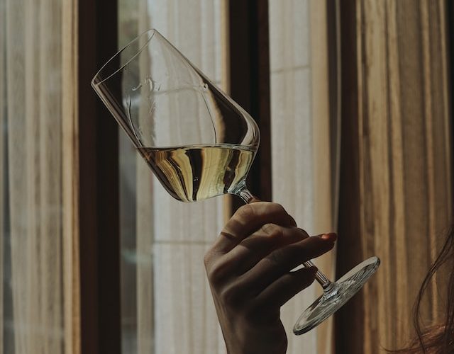 Žena si prohlíží skleničku na víno.